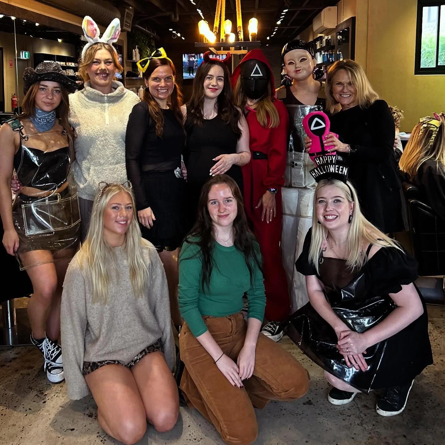 The Cropped Hair and Beauty team photographed inside the salon — ten crew members in Halloween costumes