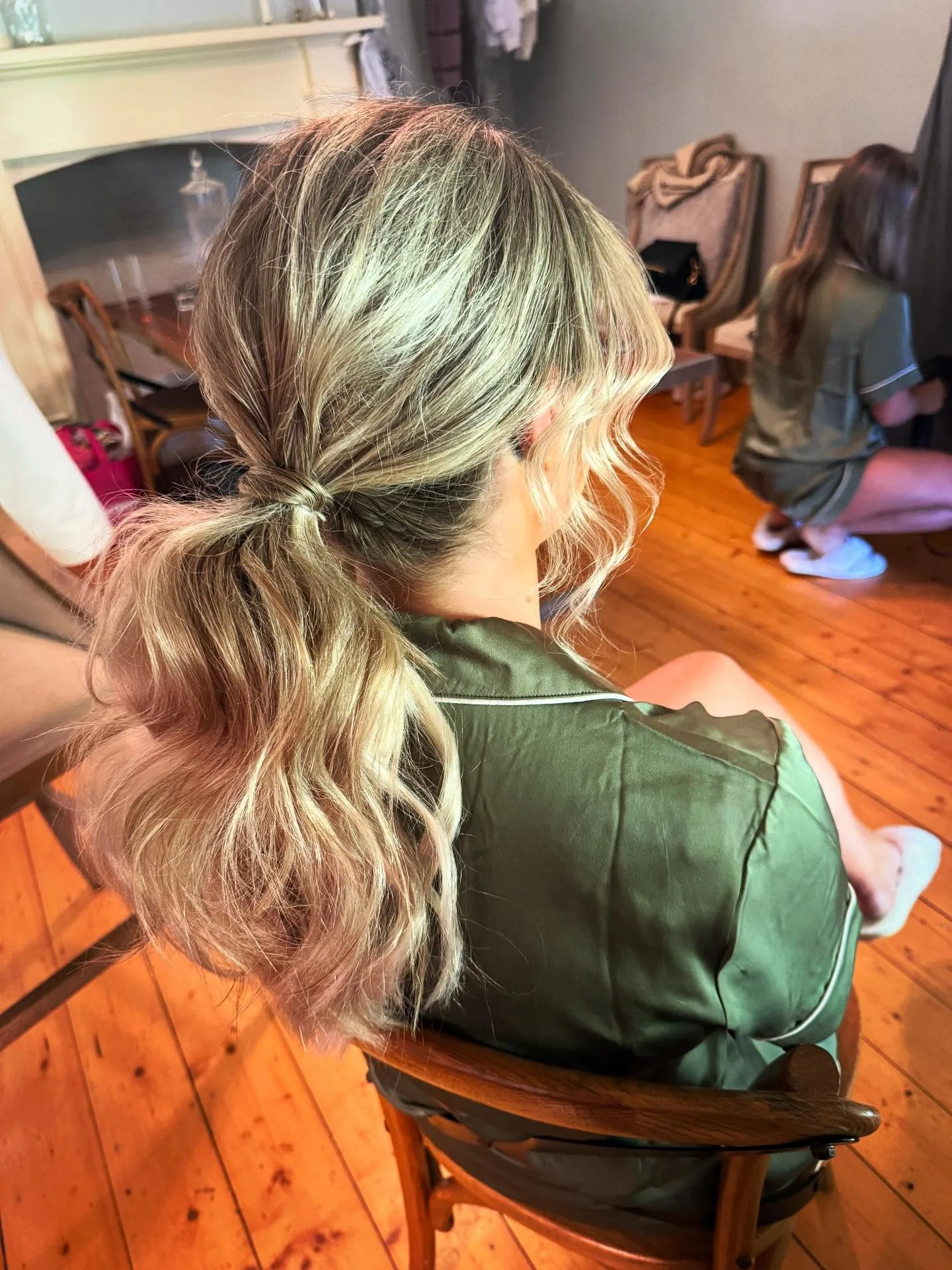Textured blonde low event ponytail, rear view — home get-ready room setting